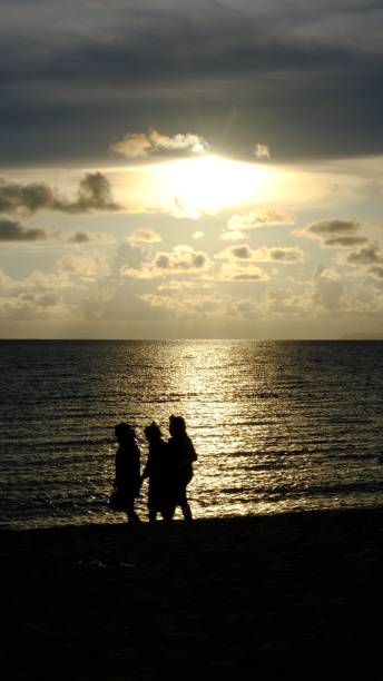 istock Silhouetted of people  walking  on  beach 1402803286