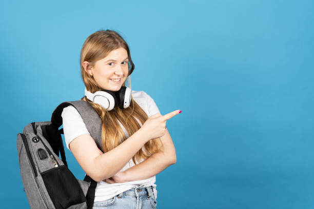 istock Pretty female student pointing at blue copy space 1402803350