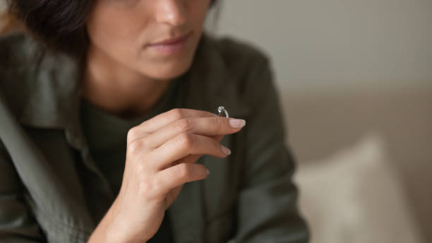 istock Depressed sad young woman taking off and holding wedding ring 1402803786