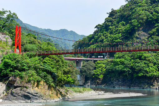 red hanging bridge or suspension bridge above the green river in the valley, Wulai, Taiwan
