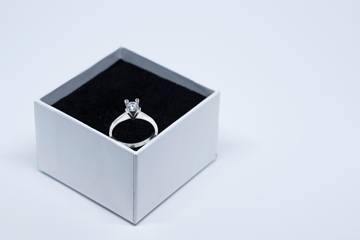 An indispensable gift for marriage proposals and anniversaries. An elegant solitaire ring photographed on a white background and black velvet surface.