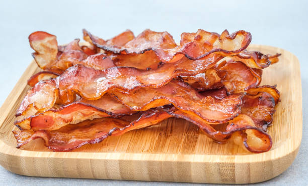 Bacon strips Fried bacon strips on the wooden plate bacon stock pictures, royalty-free photos & images