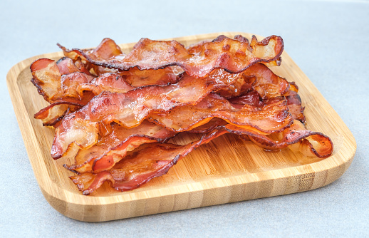 Fried bacon strips on the wooden plate