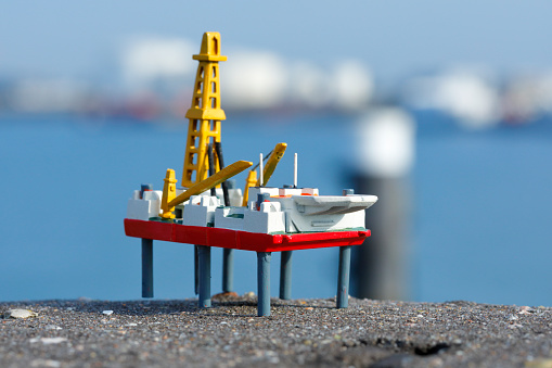 Homemade model of an oil platform in front of harbor with oil tanks