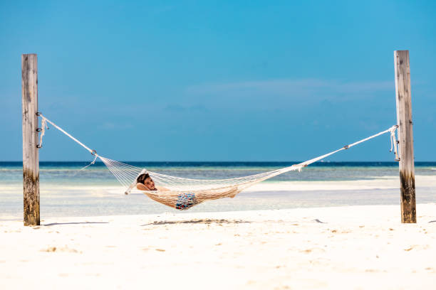 istock Little kid resting in a hammock on a white sand beach 1402813617