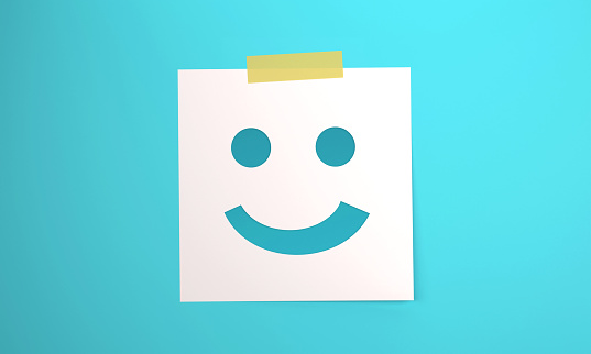 Note paper with Smiley Face icon attached to blue background with tape. Communication concept.