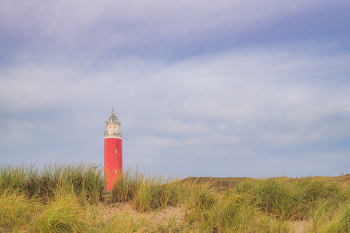 Lighthouse of Texel sticking out of the dunes along the beach.