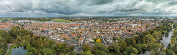 Kampen city aerial view from the city park with the river IJssel in the distance during a an autumn day with clouds and blue skies. Kampen is an ancient Hanseatic League city at the shore of the river IJssel in Overijssel, The Netherlands.