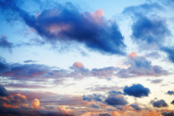 Dark cloud in orange sunset. Dramatic sunset with clouds on the sky. Bright sunlight through the blue sky at sunset or evening time.