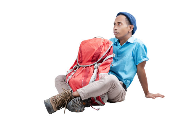 Asian man with a beanie hat sitting with his a backpack isolated over white background