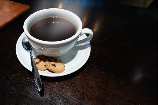 Hot black coffee in white cup and Biscuits on the table in a restaurant Bangkok