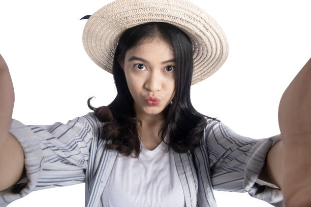 Asian woman with a hat taking a self-portrait isolated over white background