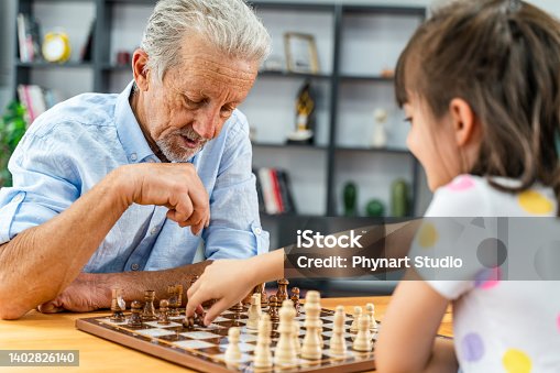istock A cheerful Grandpa is playing the chess with his little granddaughter and spending a quality time at home together 1402826140