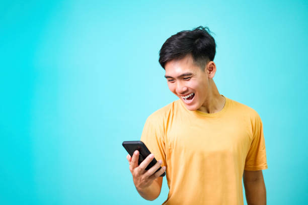 Young Asian man standing of a shocked using mobile phone. stock photo