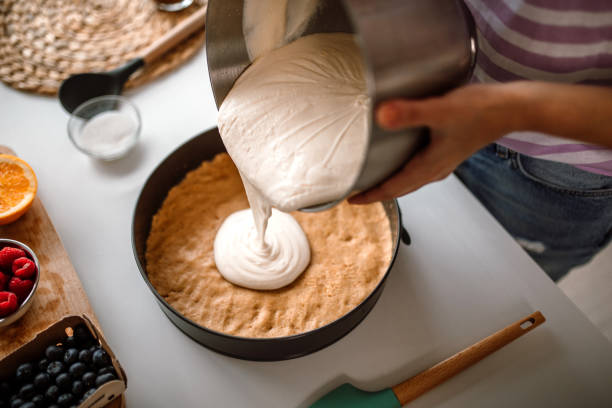 istock Woman pouring a delicious cheese cream on cake crust 1402829385