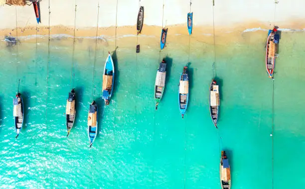 Aerial top view of the  local boat near the lagoon seashore as the tropical island in a coral reef ,blue and turquoise sea  background