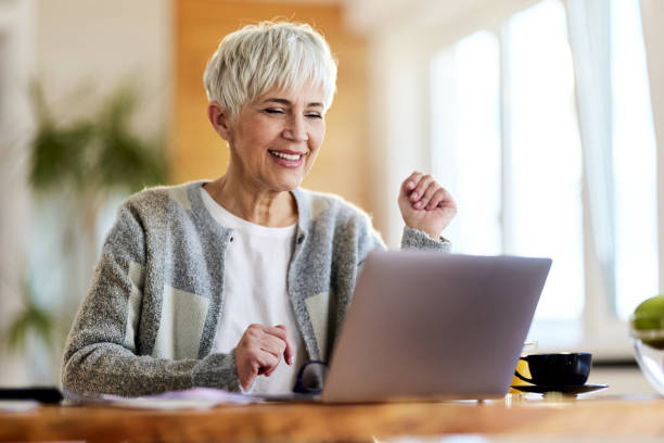 istock Happy senior woman using laptop at home. 1402830833