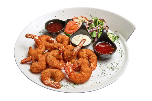 White plate with roasted shrimps, sausage and salad.  Isolated with clipping path