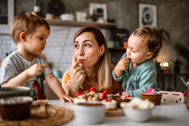 Kids making cakes with their mother at home Mother and her two children making cakes together at kitchen. Decorating it with fruits and tasting delicious healthy cakes. chocolate fingers stock pictures, royalty-free photos & images
