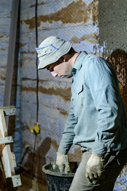 istock Black bucket with liquid mortar for the first layer of plaster for the wall. 1402832564