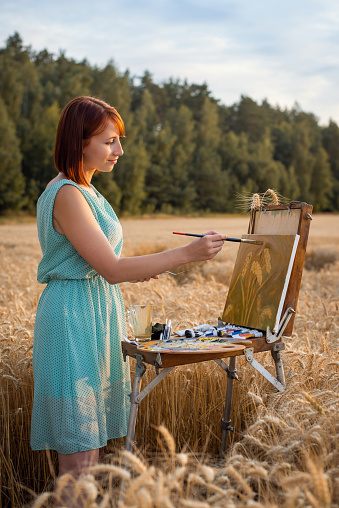 Young girl painting wheat spikelets outdoors