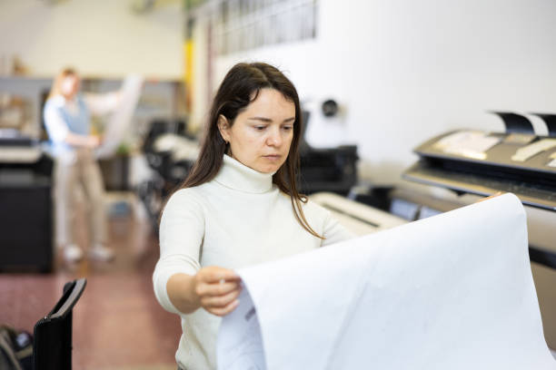 istock Woman checking large format paper after printing 1402835195