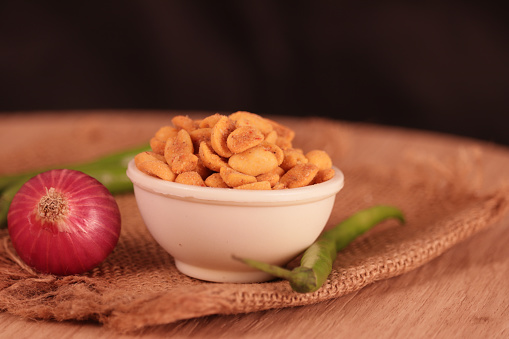 Masala shing Namkeen or roasted spicy peanuts on wooden table with onion and green chili,Masala (Spices) peanuts coated with spice