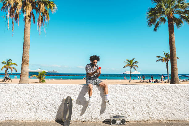 istock African man having fun doing selfie with mobile phone with beach on background - Focus on face 1402839570