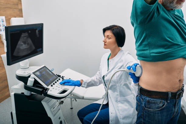 Male patient getting kidneys sonography exam standing near ultrasound specialist and ultrasound machine at hospital. Ultrasound of kidneys stock photo