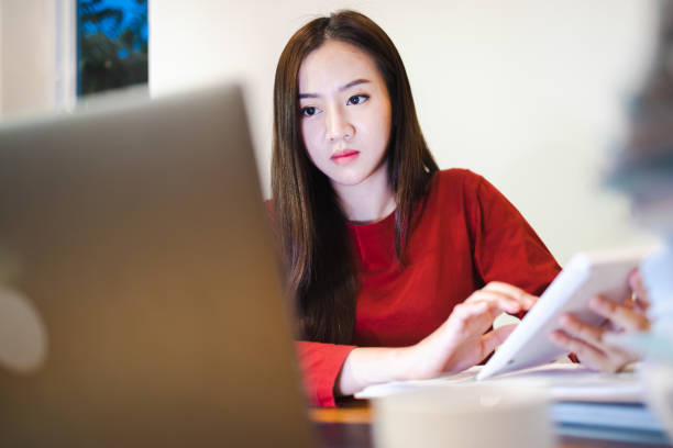 istock Asain woman using a calculator during overtime at home at night. 1402840721