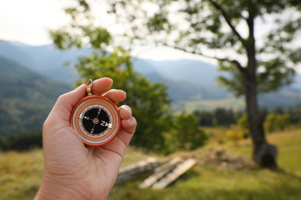 Woman using compass for navigation during journey in mountains, closeup