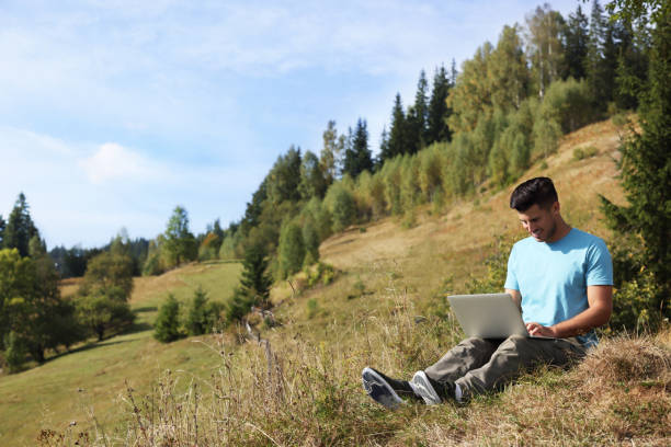 istock Man working with laptop outdoors surrounded by beautiful nature. Space for text 1402841295