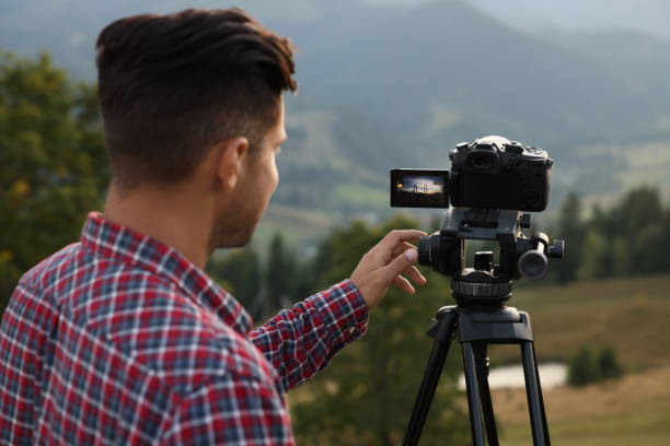 istock Man filming video with modern camera on tripod outdoors 1402841534