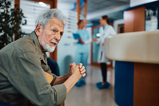 Pensive senior man in waiting room at medical clinic.