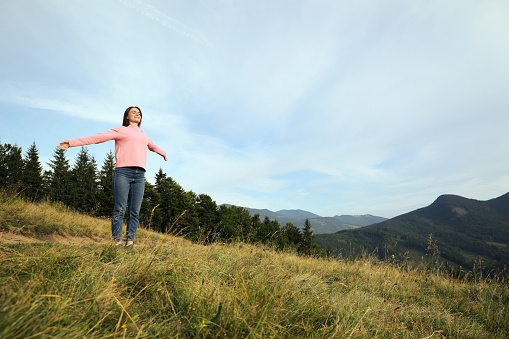 Young woman enjoying mountain landscape. Space for text