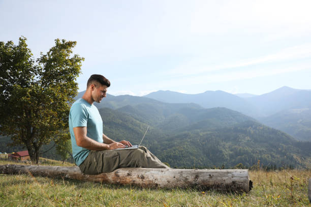 istock Man working with laptop in mountains on sunny day 1402841857