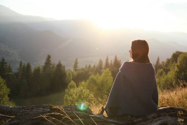 istock Woman with cozy plaid enjoying sunset in mountains, back view 1402841948