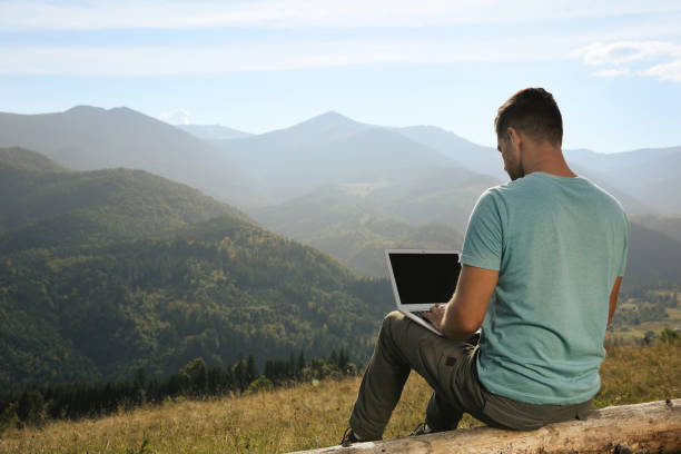 istock Man working with laptop in mountains on sunny day 1402841983