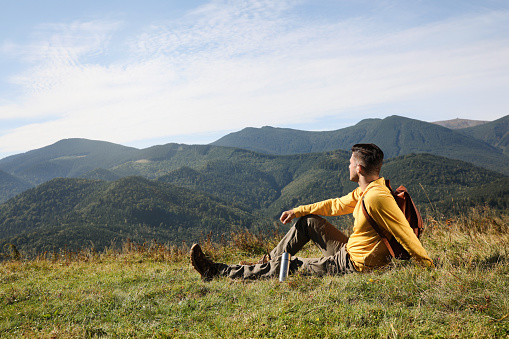 Tourist with thermos and backpack enjoying beautiful mountain landscape