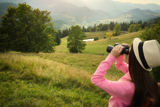 istock Young woman with binoculars in mountains, space for text 1402843092