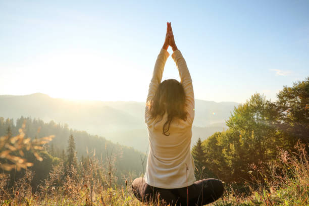 istock Woman practicing yoga in mountains at sunrise, back view 1402843542