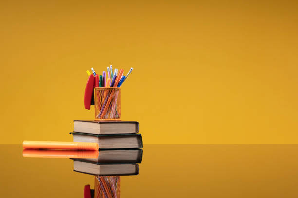 istock School accessories as a back to school concept. Writing accessories on a stack of old books and an orange marker as a background with free space for the website of a school, institute, university, an article about school education 1402843808