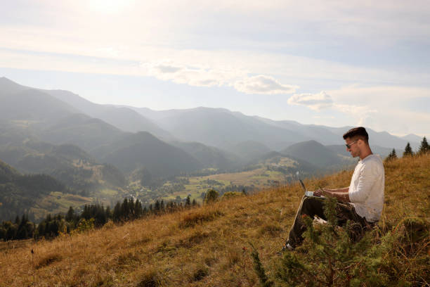 istock Man working with laptop outdoors surrounded by beautiful nature. Space for text 1402843862