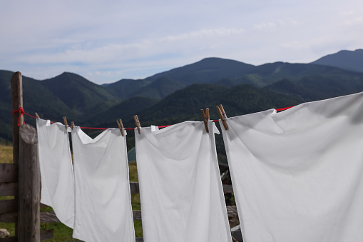 Mature hispanic woman hanging up laundry in a rural area during a sunny day. An hispanic woman pegging Out the Washing