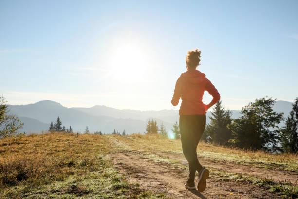 Sporty woman running in mountains, back view