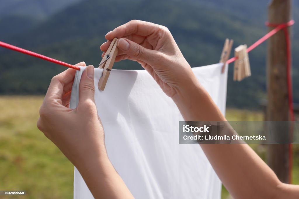 Woman hanging clean laundry with clothespin on washing line outdoors, closeup Adult Stock Photo