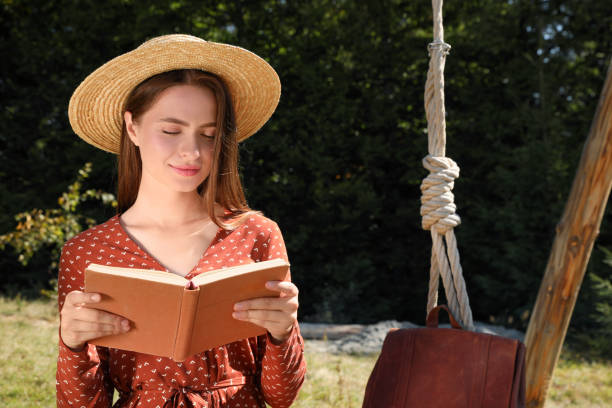 istock Beautiful young woman reading book outdoors on sunny day, space for text 1402844841