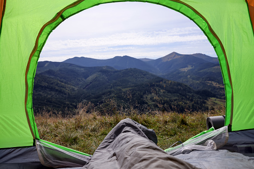 Grey sleeping bag in camping tent on hill, view from inside