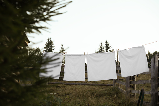 Bedclothes hanging on washing line near wooden fence outdoors