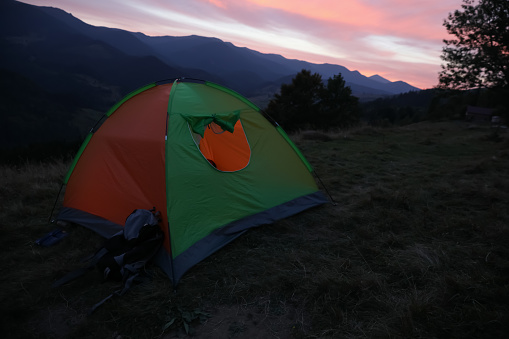 Colorful camping tent on mountain slope at sunset